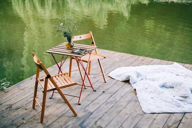 Mesa com cadeiras em um píer de madeira em um lago, ninguém.