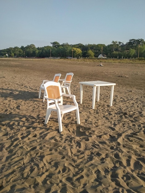 Foto mesa com cadeiras numa praia vazia.