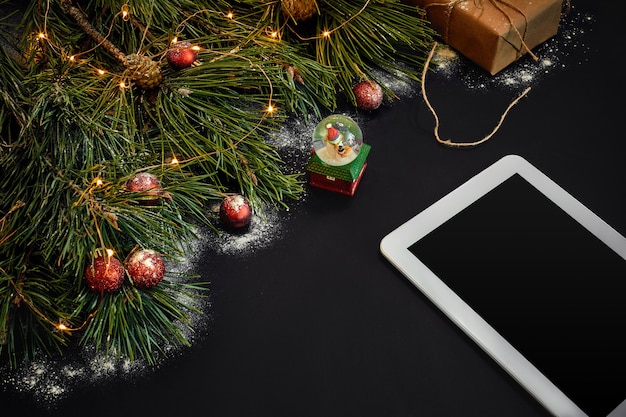 Mesa com computador tablet, estrelas de brinquedos de Natal e ramos fofos de pinheiro - espaço livre para vista superior do texto