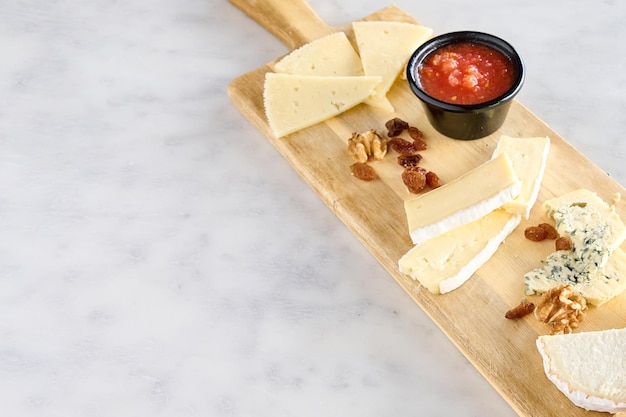 mesa com diferentes tipos de queijo, nozes, passas e geléia de framboesa