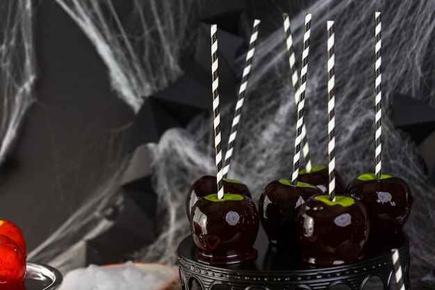 Mesa com maçãs doces coloridas e bolo para festa de Halloween.