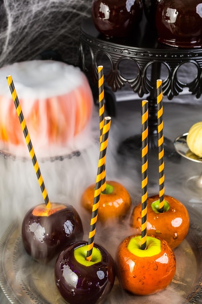 Mesa com maçãs doces coloridas para festa de Halloween.