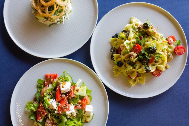 Mesa com muitos vista superior da salada. saladas diferentes na mesa de concreto, vista superior. salada de legumes, salada com salmão fumado, ceviche e stracciatella.