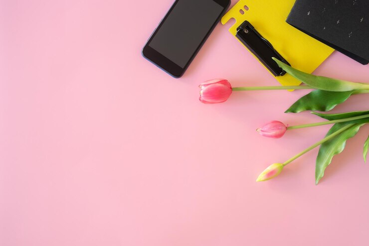 Foto mesa com notebook flor de tulipa portátil e caneta no chão rosa, vista de cima plana