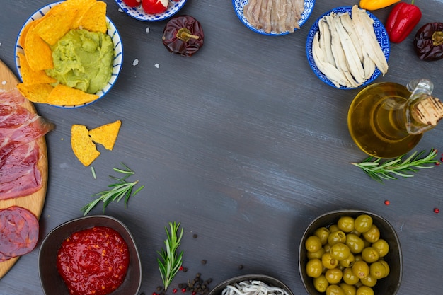 Foto mesa com tapas espanholas - anchovas com pimentos padron, jamon, croquetes, guacamole e azeitonas