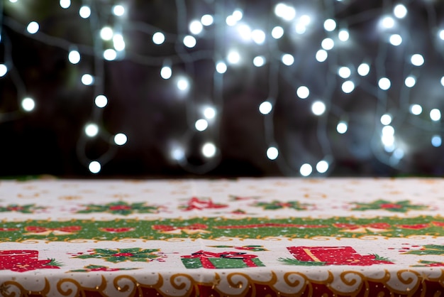 Foto mesa com toalha de mesa mesa com lenço de mesa de natal vazio com luzes de natal desfocadas no fundo fundo escuro foco seletivo