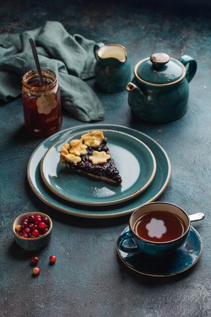 Mesa com torta de frutas vermelhas, xícaras quentes com chá de limão e geleia