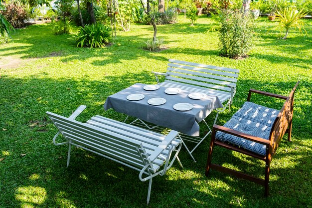 Mesa de comedor familiar informal azul de seis asientos en el patio trasero con césped verde y árboles