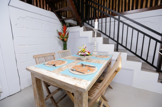 Una mesa de comedor en una habitación con un juego de platos y un arreglo floral.