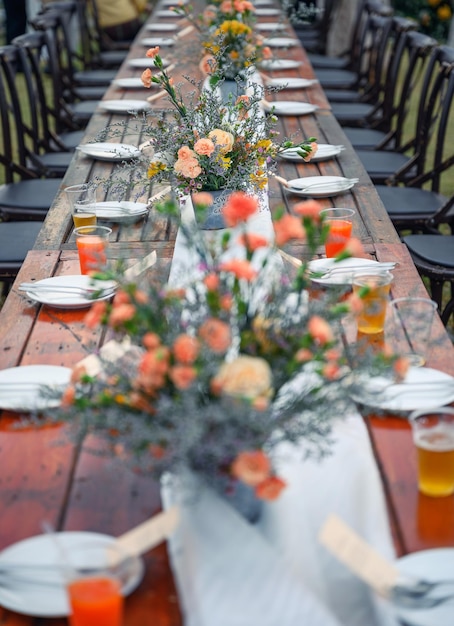 Mesa de comedor de madera estilo boda rústica con decoración de flores y vajilla