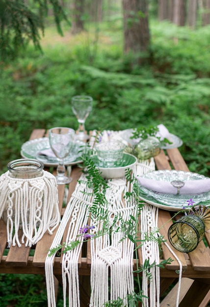 Mesa de comedor de recepción de boda estilo boho con mantel de macramé, decoración en una mesa de madera rústica