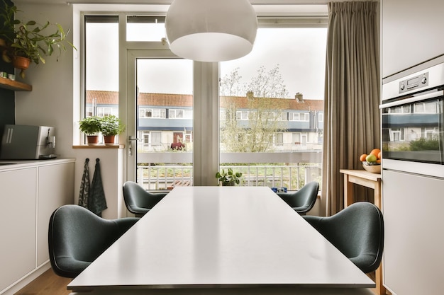 Foto una mesa de comedor y sillas en una habitación con grandes ventanales que dan al paisaje urbano.