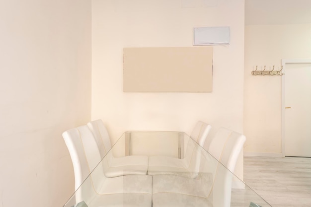 Mesa de comedor de vidrio con sillas tapizadas en cuero blanco
