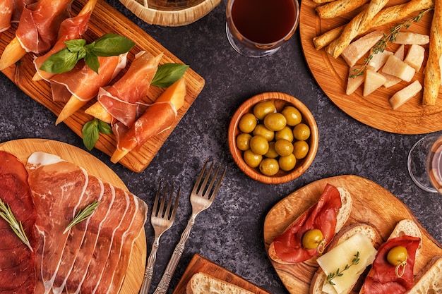 Mesa de comida italiana con jamón, queso, aceitunas.