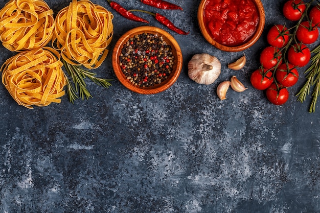 Mesa de comida italiana con pasta, especias y verduras.