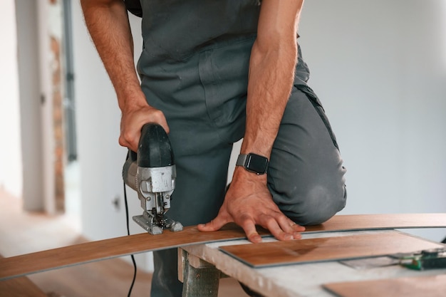 En la mesa cortando tablas con el taladro El hombre está instalando un nuevo piso de madera laminada