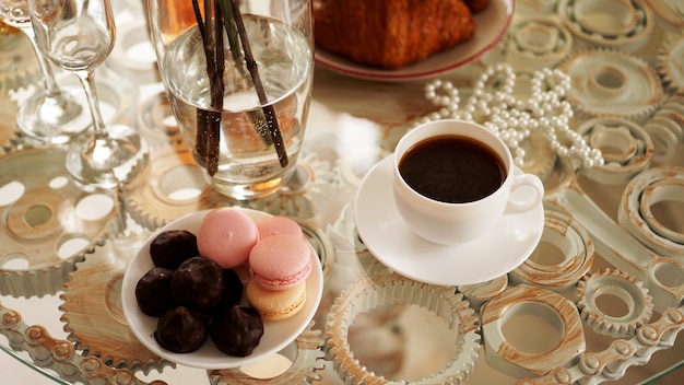 Mesa de cristal con una taza de café, macarrones dulces. Una foto festiva y romántica. Mañana después de la cita