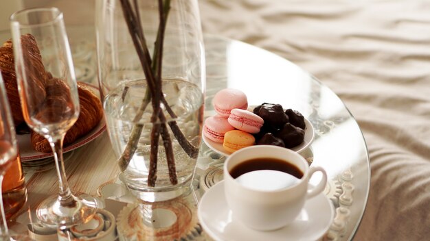 Mesa de cristal con una taza de café, macarrones dulces. Una foto festiva y romántica. Mañana después de la cita