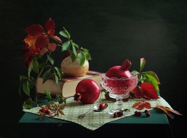 Una mesa con un cuenco de granadas y un libro en ella