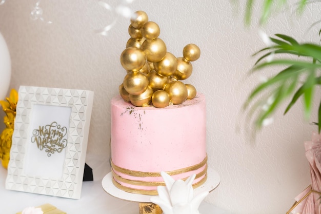 Mesa de cumpleaños de vacaciones con pastel y globos decoración rosa y dorada