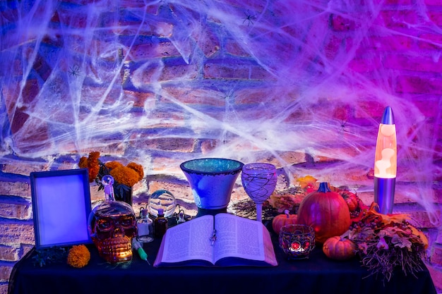 Foto mesa da bruxa de halloween, altar com objetos mágicos, livro antigo para um feitiço, velas acesas e abóbora