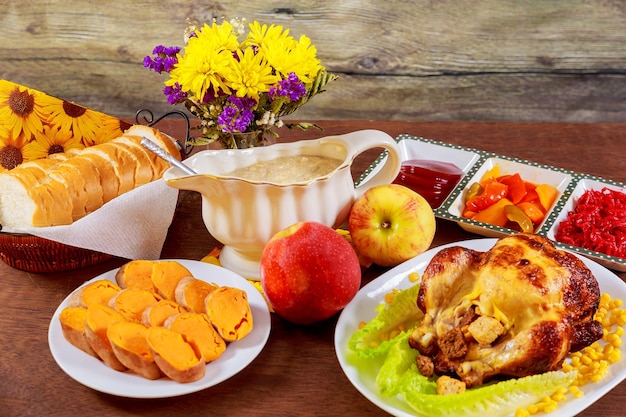 Mesa de ação de graças de frango assado servido com peru decorado com velas e folhas de outono brilhantes