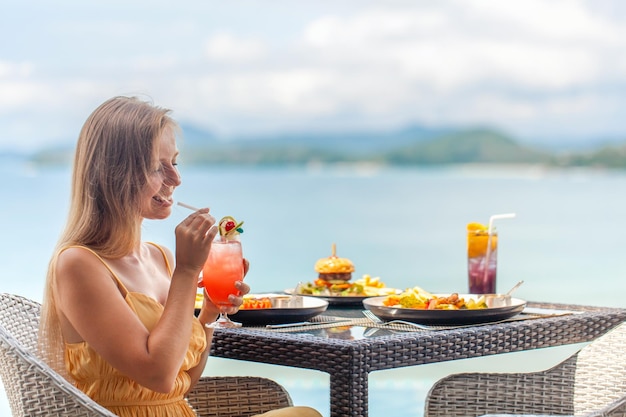 Mesa de almoço e mulher de viagens de luxo na vista de férias do mar aproveitam as férias