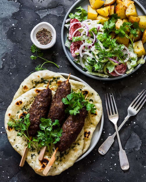 Mesa de almoço estilo mediterrâneo Kebab de carne alho ervas naan molho de iogurte salada de legumes batatas assadas