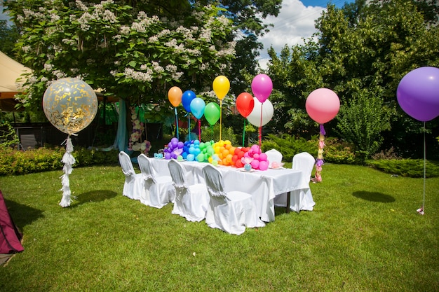 Mesa de aniversário com balões de arco-íris. Férias de verão no parque.