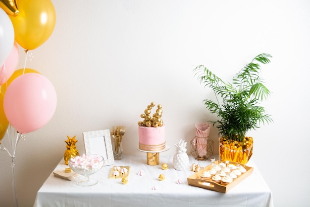 Mesa de aniversário de férias com decoração de bolo e balões rosa e dourado