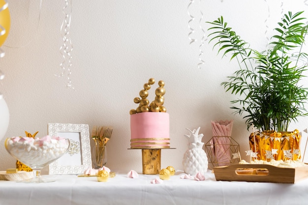 Mesa de aniversário de férias com decoração de bolo e balões rosa e dourado