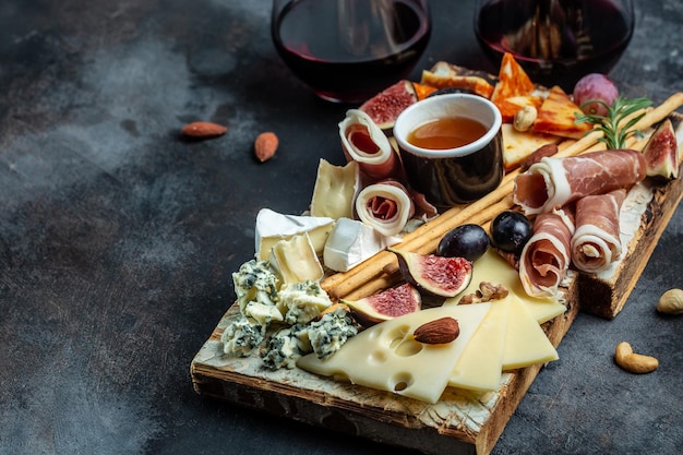 Mesa de aperitivos com antepastos italianos e vinho em copos queijo presunto nozes frutas pão palitos Delicioso conceito de comida equilibrada