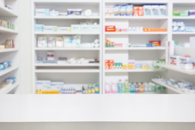 Mesa de balcão de farmácia de farmácia com backbround abstrato desfocado com medicamentos e produtos de saúde nas prateleiras