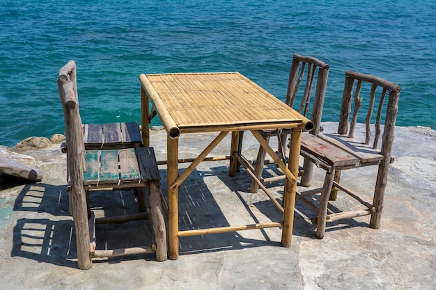 Mesa de bambu e cadeiras de madeira no café vazio ao lado da água do mar na praia tropical ilha koh phangan tailândia