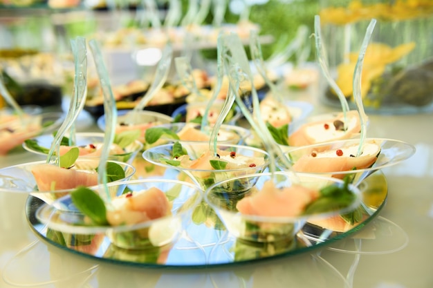 Mesa de buffet com expositor de petiscos de salmão e frutos do mar em espelhos circulares