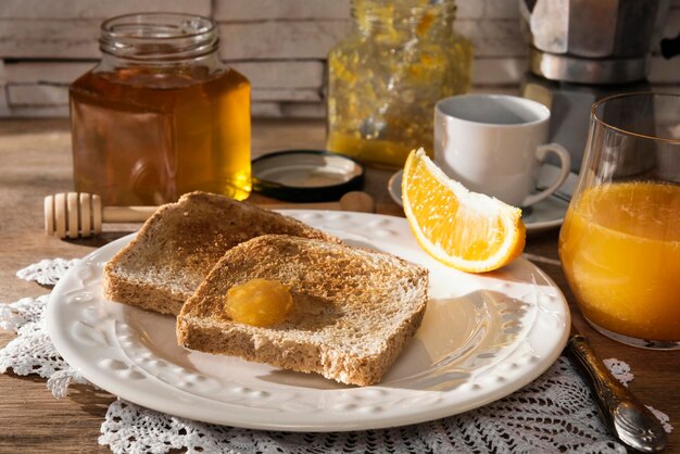 Mesa de café da manhã com torradas, marmelada de laranja, mel, suco de laranja e café expresso