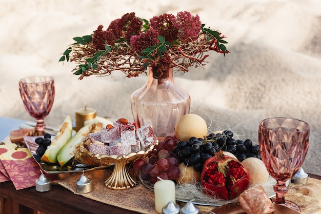 mesa de casamento com um vaso transparente copos de frutas e doces