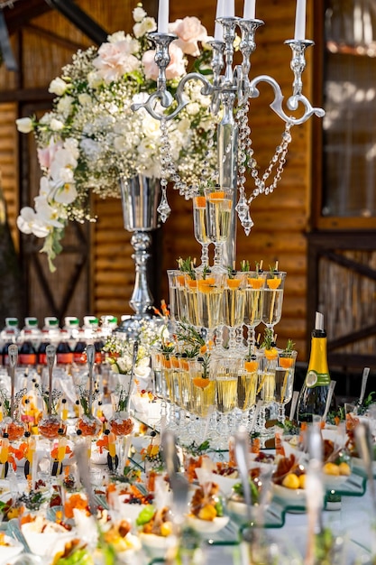 Mesa de casamento de cor branca decorada com velas de flores de candelabro e copos com champanhe Closeup