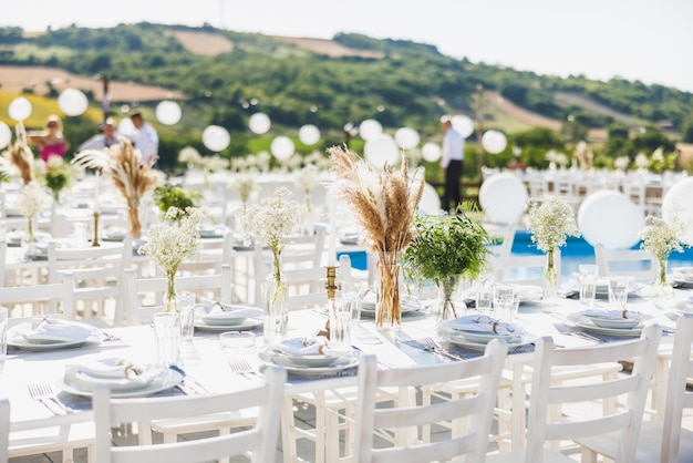 Mesa de casamento montada em estilo boho com grama de pampas perto de vinhedo.