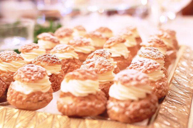 Mesa de catering com bolos de chocolate fatiados, decorados com framboesas frescas e nozes.