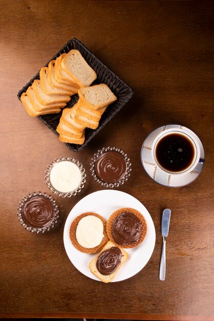 Mesa de centro com torradas e propagação de chocolate branco chocolate e avelã espalha vista superior na mesa de madeira