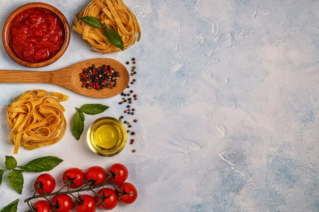 Mesa de comida italiana com macarrão, temperos e legumes.