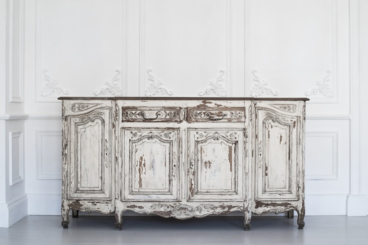 Foto mesa de cômoda branca antiga com tinta descascada em elementos roccoco de molduras de estuque de baixo-relevo de design de parede de luxo