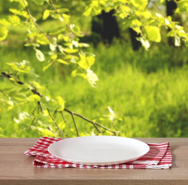 Mesa de cozinha com um prato vazio sobre um fundo verde embaçado do lado de fora