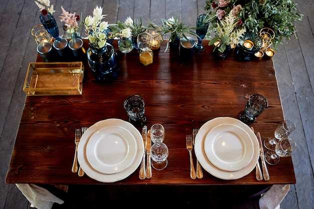 Mesa de decoração recém-casados pratos azuis garrafas de flores e velasFloricultura de casamento