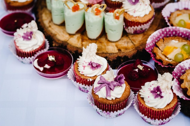 Mesa de doces pratos de bolos e muffins mesa com buffet de doces mesa de sobremesa para uma festa guloseimas para o casamento barra de doces decorada deliciosa