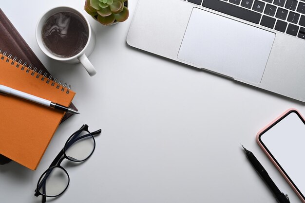 Mesa de escritório branca de vista superior com notebook portátil óculos pone móvel e xícara de café