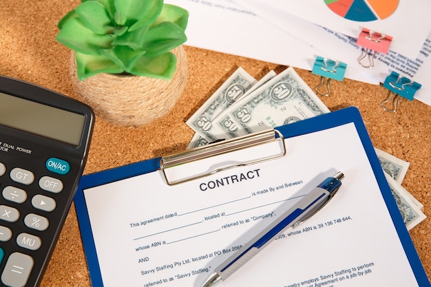 Mesa de escritório, calculadora, caneta e documentos com contrato em branco