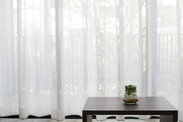 mesa de escritório com a planta de jardim na textura branca do fundo das janelas da cortina.