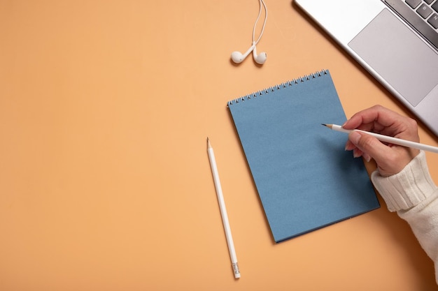 Mesa de escritório com bloco de notas de papel azul em branco e laptop feminino em fundo colorido vista superior e espaço de cópia para texto